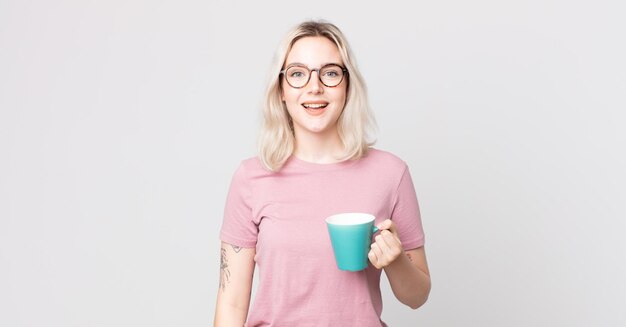 Mulher jovem e bonita albina parecendo feliz e agradavelmente surpresa com uma caneca de café