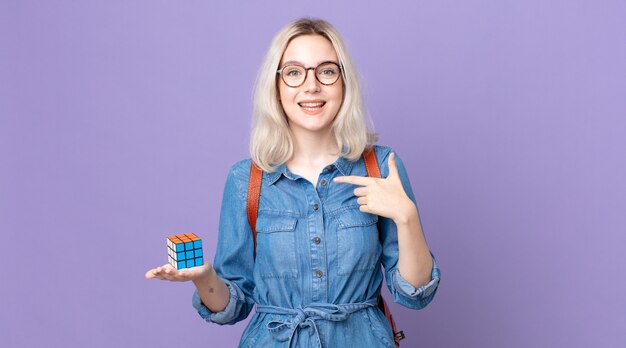 Mulher jovem e bonita albina se sentindo feliz e apontando para si mesma com um jogo de inteligência animado e resolvendo