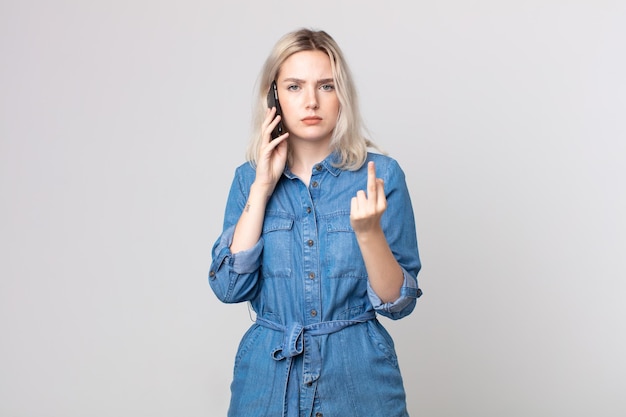 Mulher jovem e bonita albina se sentindo irritada, irritada, rebelde e agressiva e falando com um smartphone