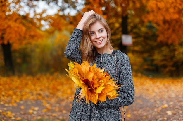 Mulher jovem e bonita alegre com um casaco cinza da moda