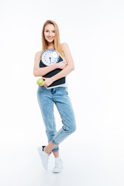 Mulher jovem e bonita alegre posando com escamas e maçã verde sobre fundo branco