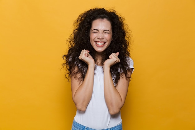 Mulher jovem e bonita animada posando isolada em amarelo.