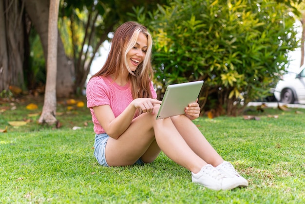 Mulher jovem e bonita ao ar livre segurando um tablet