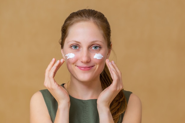 Foto mulher jovem e bonita aplicando cosméticos faciais com as mãos