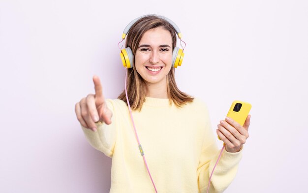 Mulher jovem e bonita apontando para a câmera escolhendo você. fones de ouvido e conceito de telefone