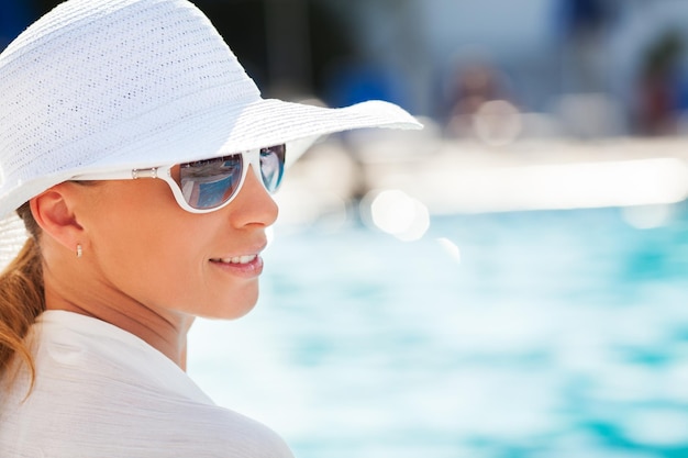 Mulher jovem e bonita, aproveitando o sol à beira da piscina