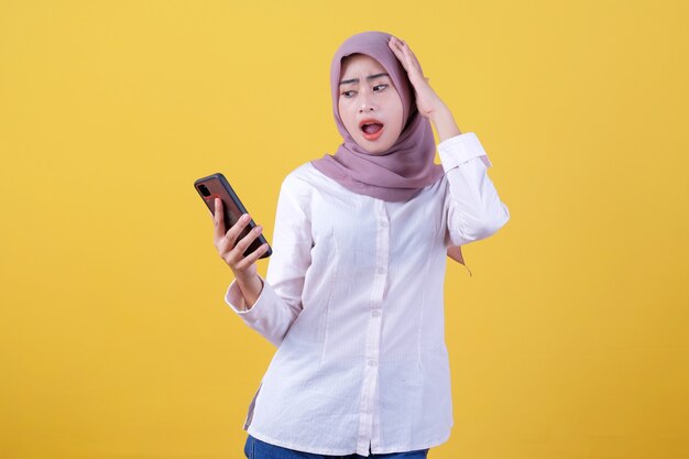 Mulher jovem e bonita asiática chocante conversando ao telefone usando hijab