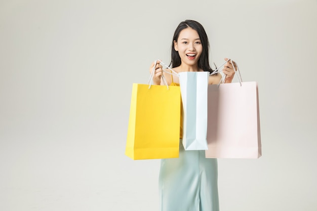 Mulher jovem e bonita asiática com sacolas de compras isoladas