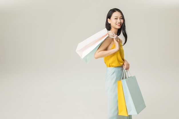 Mulher jovem e bonita asiática com sacolas de compras isoladas