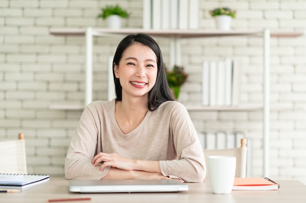 Mulher jovem e bonita asiática trabalhando em casa e se sentindo feliz sorrindo com uma expressão alegre