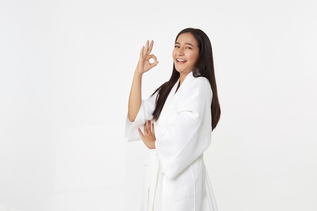 Mulher jovem e bonita asiática vestindo roupão de banho sorrindo com pele limpa e fresca. Felicidade e alegre com emocional positivo isolado no fundo branco