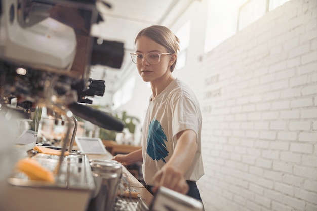 Mulher jovem e bonita barista trabalhando em uma cafeteria