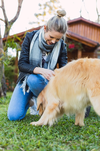 Mulher jovem e bonita caucasiana com lenço olhando para o cachorro rindo ao ar livre pela manhã