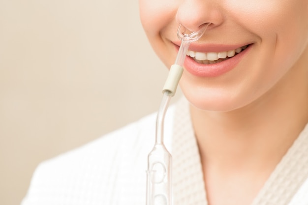 Mulher jovem e bonita caucasiana feliz recebendo inalador nasal com óleo essencial, sorrindo em um spa