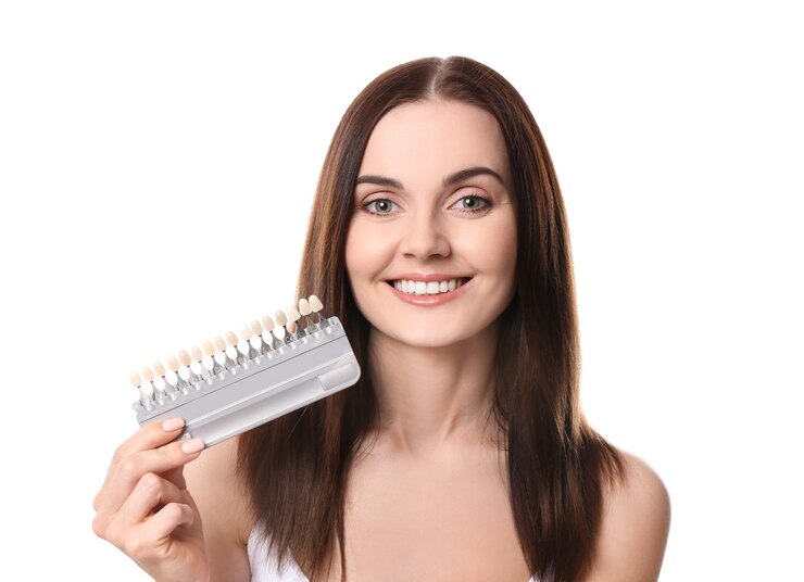 Foto mulher jovem e bonita com amostras de cores de dentes em fundo branco