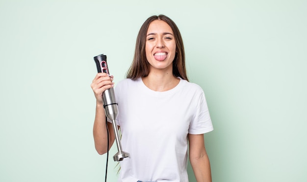 Mulher jovem e bonita com atitude alegre e rebelde, brincando e mostrando a língua. conceito de batedeira