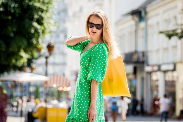 Mulher jovem e bonita com bolsa ecológica de linho amarela no fundo da cidade.