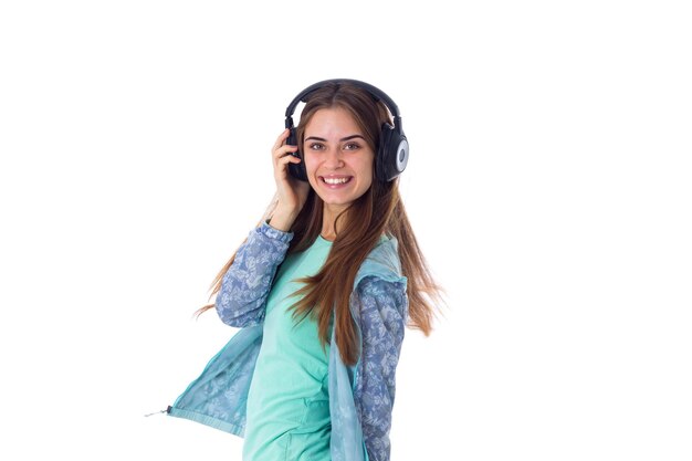 Mulher jovem e bonita com cabelo comprido na camisa azul, ouvindo a música em fones de ouvido pretos