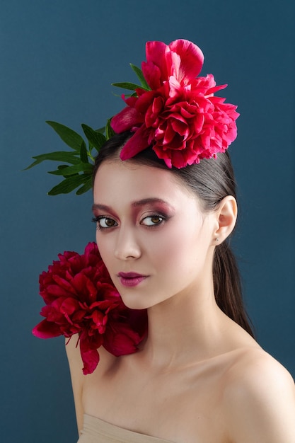 Mulher jovem e bonita com cabelo comprido posando com peônias na cabeça Retrato de uma menina com flores na cabeça