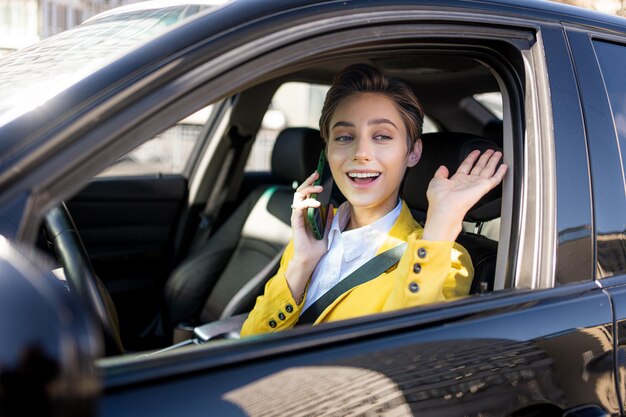 Mulher jovem e bonita com cabelo curto dirige carro na cidade