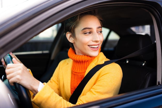 Foto mulher jovem e bonita com cabelo curto dirige carro na cidade