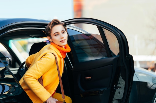 Mulher jovem e bonita com cabelo curto dirige carro na cidade