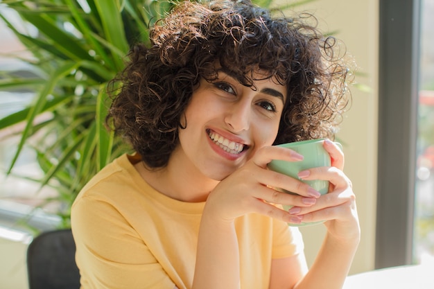 Mulher jovem e bonita com cabelo encaracolado dentro de casa