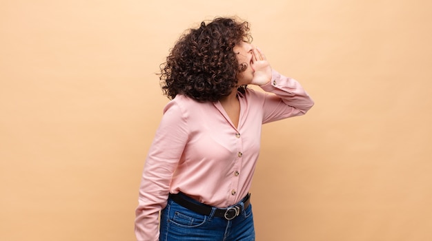 Mulher jovem e bonita com cabelo encaracolado e uma camisa rosa