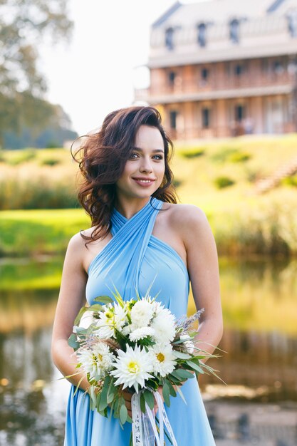 Mulher jovem e bonita com cabelo encaracolado posando com buquê