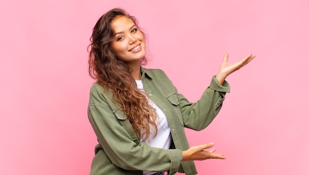 Mulher jovem e bonita com camisa aberta jeans verde posando na parede rosa