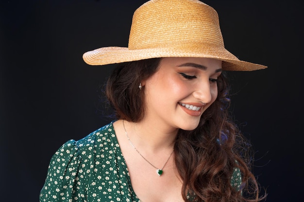 Mulher jovem e bonita com chapéu de palha posando contra um fundo preto