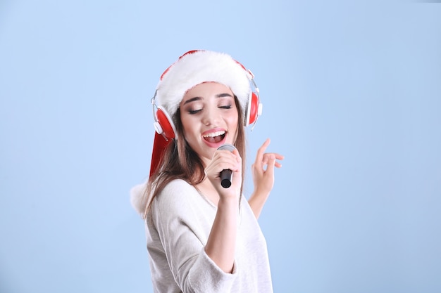 Mulher jovem e bonita com chapéu de Papai Noel cantando canções de Natal