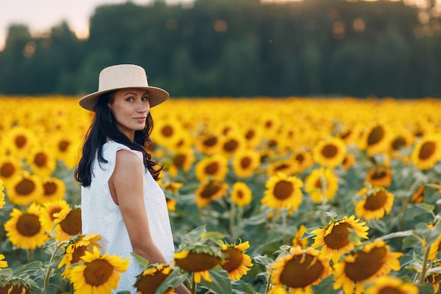 Mulher jovem e bonita com chapéu no campo de girassol.