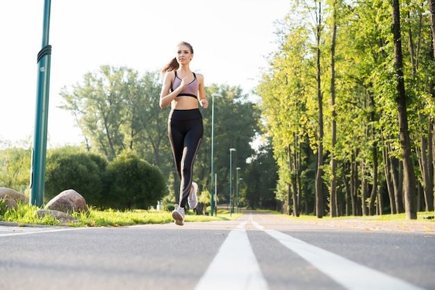 Mulher jovem e bonita com corpo magro perfeito correndo ao ar livre. fitness e conceito de corrida.