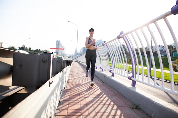 Mulher jovem e bonita com corpo magro perfeito correndo ao ar livre. Fitness e conceito de corrida.