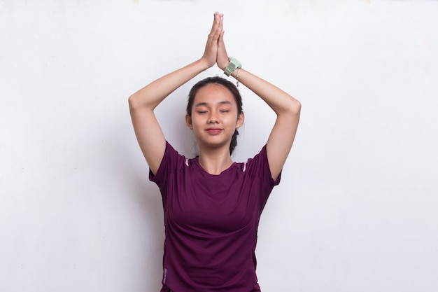 Mulher jovem e bonita com esportes asiáticos fazendo ioga relaxante e meditando sobre fundo branco.
