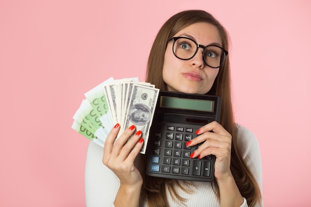 Mulher jovem e bonita com euros e dólares em fundo rosa