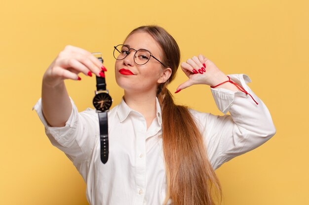 Mulher jovem e bonita com expressão de orgulho, mostrando o relógio