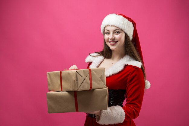 Mulher jovem e bonita com fantasia de Papai Noel contra o fundo vermelho.