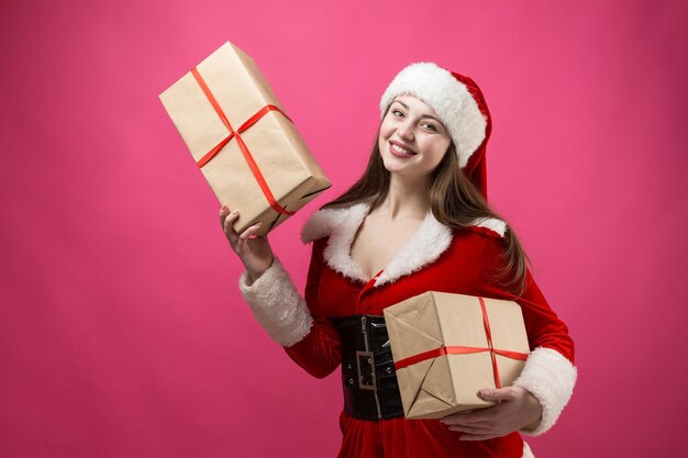 Mulher jovem e bonita com fantasia de Papai Noel contra o fundo vermelho.