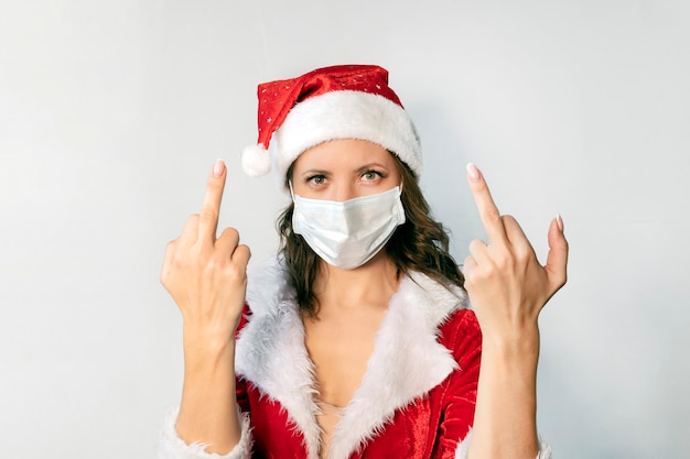 Mulher jovem e bonita com fantasia de Papai Noel vermelha e máscara médica protetora contra vírus. Conceito que celebra o Natal na covid 19 pandemia e quarentena. A Sra. Papai Noel odeia o auto-isolamento