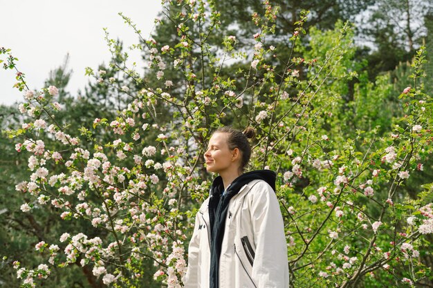 Mulher jovem e bonita com flores da primavera curtindo a natureza e rindo no jardim da primavera Mulher segurando o galho de uma macieira Conceito de liberdade e felicidade Primavera