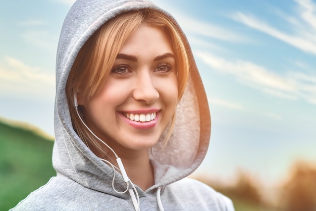 Mulher jovem e bonita com fones de ouvido feliz depois de uma boa corrida no parque da cidade