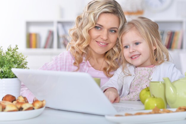 Mulher jovem e bonita com garota usando laptop em casa