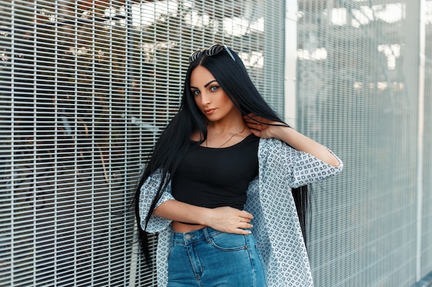 Mulher jovem e bonita com longos cabelos negros e uma camisa branca na rua