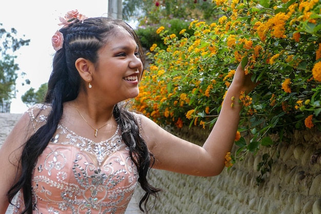 Mulher jovem e bonita com maquiagem e vestido cor de melão tocando flores em um jardim