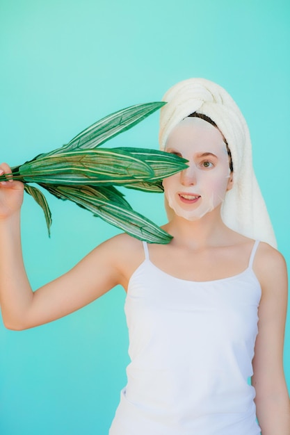 Mulher jovem e bonita com máscara facial no rosto segurando fatias de pepino.