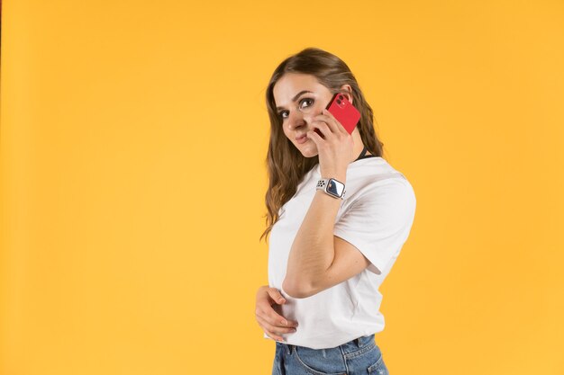 Mulher jovem e bonita com novo modelo de smartphone e smartwatch falando no smartphone.