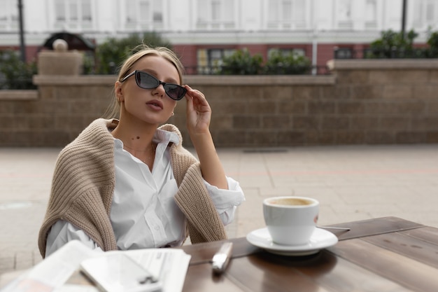 Mulher jovem e bonita com óculos em um café de rua