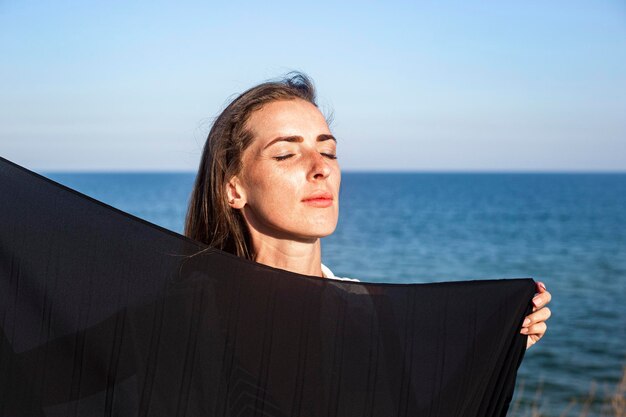 Mulher jovem e bonita com os olhos fechados no fundo do mar e do céu.